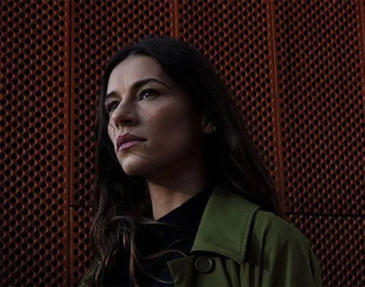 Lady in green coat in front of red wall