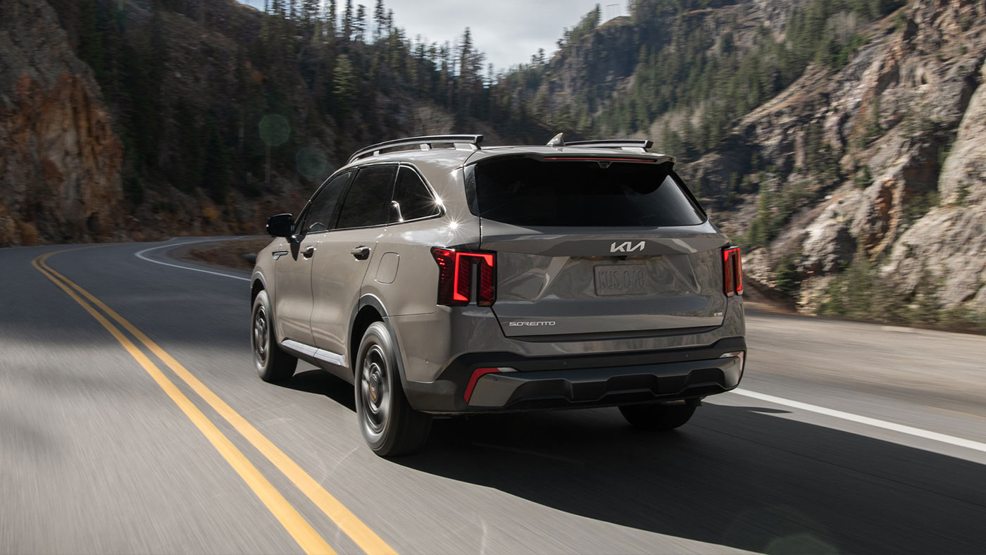 Vue arrière d’un Kia Sorento X-Pro couleur Gris loup se déplaçant sur la route.
