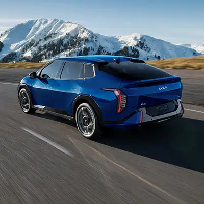 Blue Kia EV4 electric sedan driving in winter with heat pump